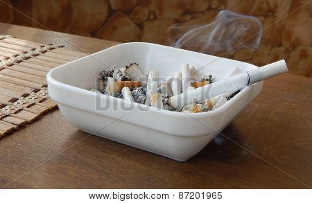 Ashtray with smoke cigarette and butts