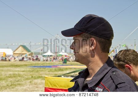 policeman in a baseball cap looks thoughtfully into the distance