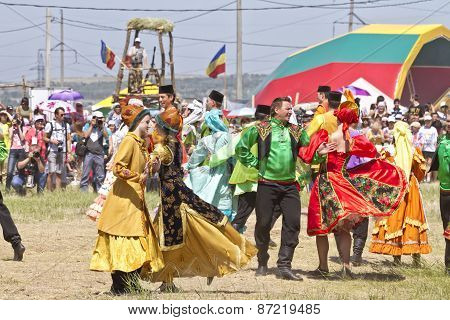 Men and women in national costumes dance traditional folk dances