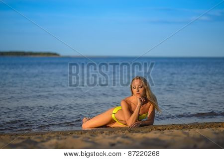 young woman in green bikini posing on a beach