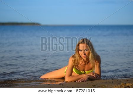 young woman in green bikini posing on a beach