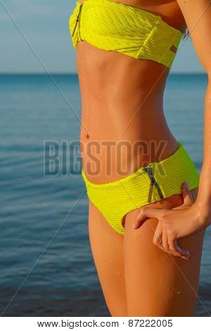 young woman in green bikini posing on a beach