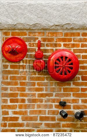 Red fire alarm sprinkler and hidrant in red brick wall