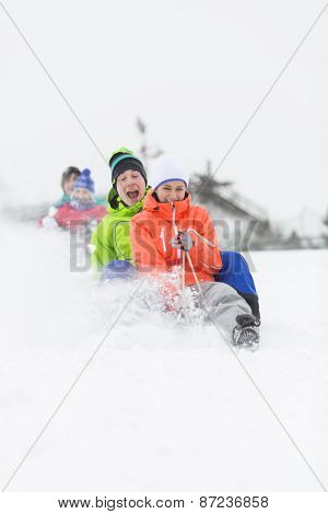 Excited young friends sledding in snow