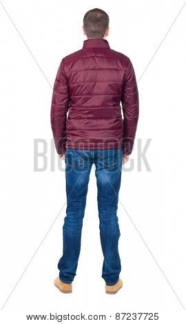 Back view of handsome man in blue windcheater looking. Standing young guy in jeans. Rear view people collection.  backside view of person.  Isolated over white background.