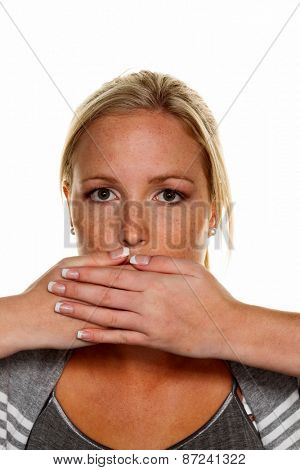 a young woman holds her hand to her mouth. symbolic photo for silent, say nothing and deny the statement