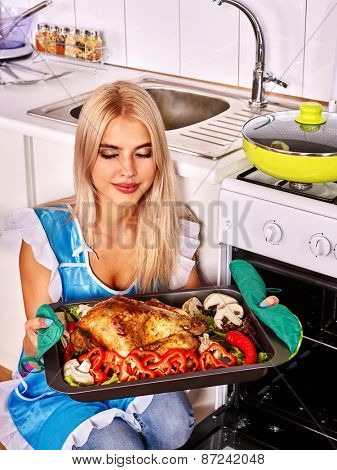Young woman cooking chicken at kitchen. Eyea closed.