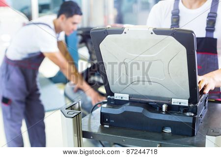 Asian Chinese car mechanics checking auto engine with diagnostics tool in his workshop