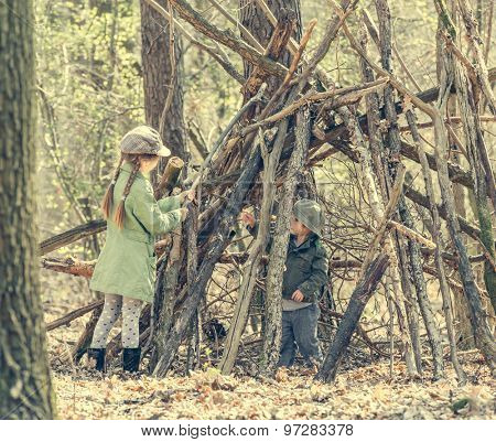 little girl with ter sister  in the wood near the hut. Photo in retro style