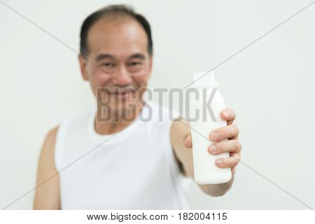 Asian senior man holding bottle of milk.