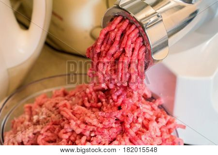 Closeup of minced raw meat coming out from grinder