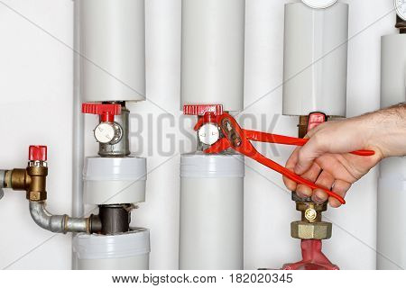repair man is fixing a valve in a heating room