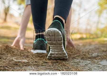 Girl in sports pants and shoes stands at the start before running leaning hands