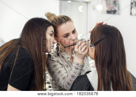makeup teacher training her student girl to become makeup artist. Makeup lesson at beauty school. Make-up artist work in her studio. Real people. Closeup of visagiste applying makeup