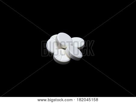 Composition of the white round pills isoltaed on black background