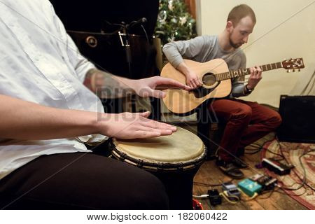 stylish solo guitarist and percussionist playing on a concert on a background of his band
