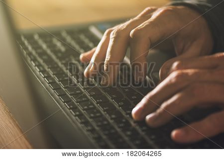 Computer programmer and hacker hands typing laptop keyboard close up low key with selective focus
