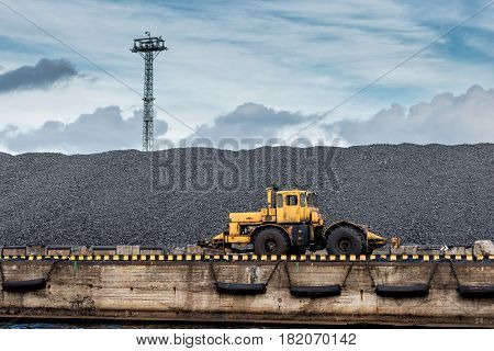 Tractor at coal pile coal shipping terminal.