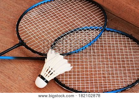 Badminton rackets and badminton balls are placed on a brown background