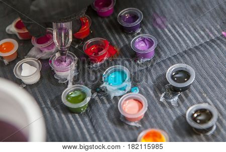 Tattoo artist mixing colors into small cup for ink. Closeup