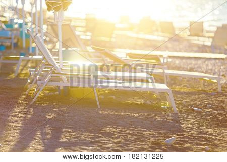 Loungers on beach deserted seaside at amazing sunrise.