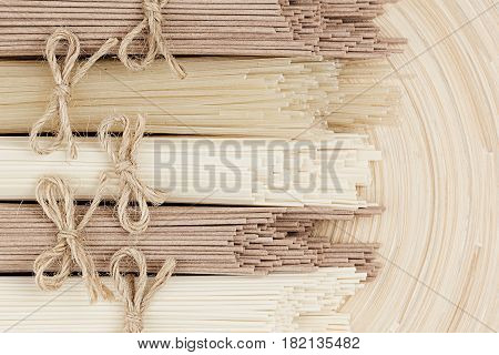 Assortment bundles of uncooked asian noodles close up on white wooden board background top view.