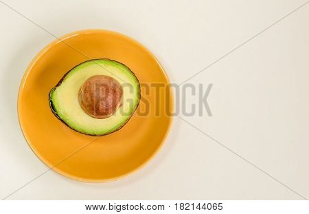 Avocado fruit green half with seed on the yellow plate isolated white background