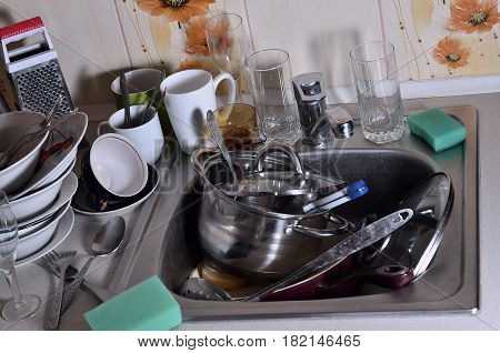 A Huge Pile Of Unwashed Dishes In The Kitchen Sink And On The Countertop