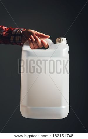 White unlabeled plastic 5 liters tank canister in female hand chemistry and chemical liquids mock-up container