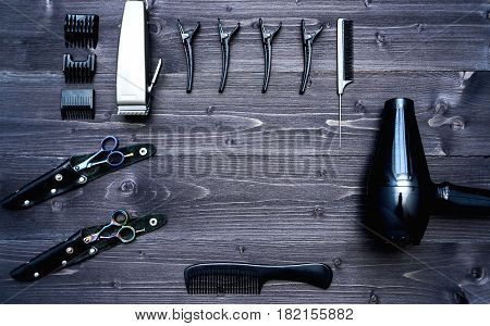 Hairdresser tools on wooden background. Top view on wooden table with scissors hairclips comb clipper and hairdryerl free space. Barbershop manhood concept
