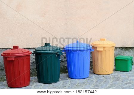 Several bio-waste container of different colors on a house wall