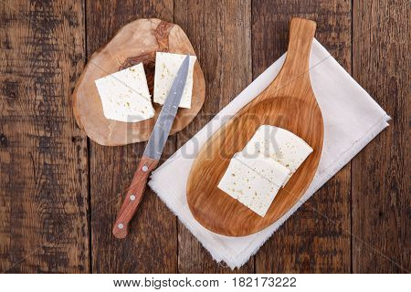 Sliced fresh brined white cheese from cow milk on wooden table. Top view.