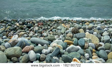 The stony sea shore. In the foreground there is a sea pebble of various sizes. Pure water. Can be used as a background.