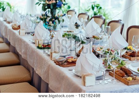 Table setting. Table served for wedding banquet close up view. White napkin on a white empty plate on a dining table