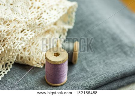 Vintage wood spools with lilac and grey threads on folded wool fabric cotton lace swing hobby concept copyspace header for website