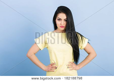 portrait of attractive young brunette woman in yellow dress on the blue background.