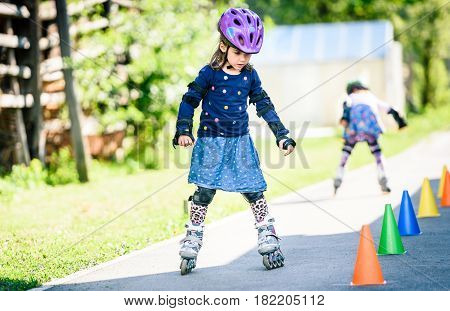 Children Learning To Roller Skate On The Road With Cones.