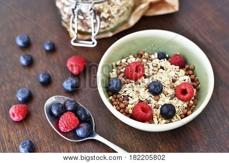 Breakfast bowl with fresh berry fruits. Cereals with blueberries and raspberries on a wooden table.