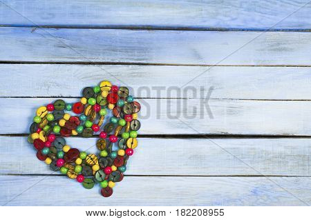 Colorful glass beads hearts on wooden background.