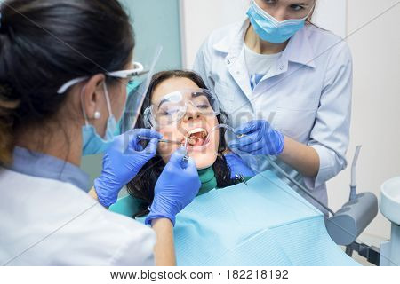 Two dental doctors and patient. Procedure at the dentist office.