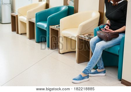 Young Girl Sitting In Waiting Room On The One Of Row Of Blue And Ivory Chairs In Hall. Selective Foc