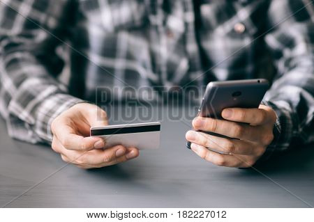 A man uses a mobile phone to pay for tariffs and services purchased on the Internet