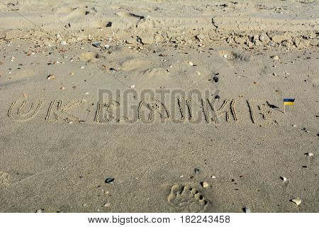 Miniature Ukrainian flag on the Black Sea beach with the text "Ukraine"