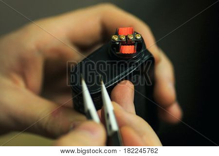 Vape After-sales Service Of The E-cigarette. Male Hands Regulate Electronic Cigarette Coils With Pin