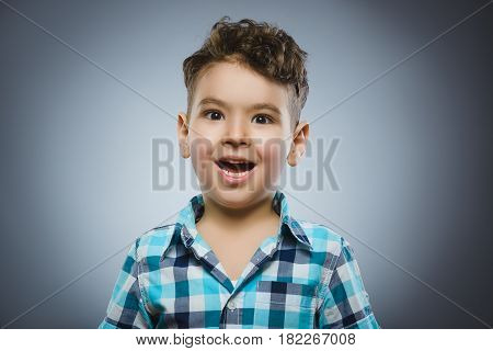 Closeup Portrait of handsome boy with astonished expression while standing against grey background.