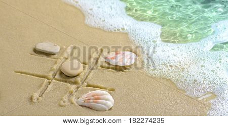 Soft wave with foam, a tic tac toe game drawn in the sand on the beach