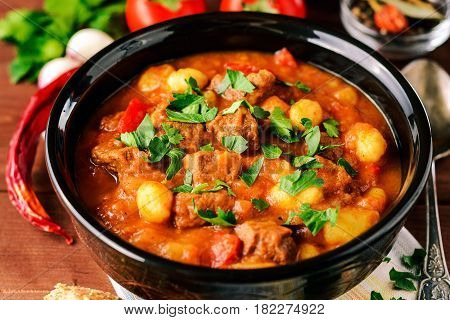 Goulash in ceramic bowl on wooden background. Traditional hungarian soup. Rustic style. Selective focus.