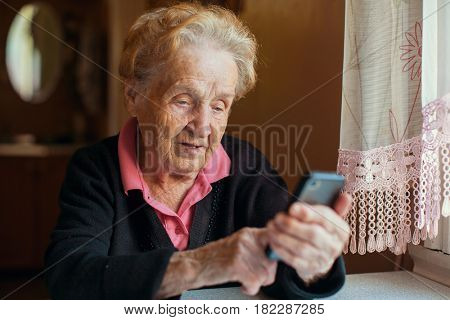 An old woman uses a smart phone.
