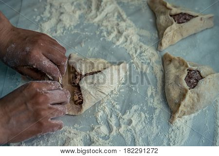 Finishing of wrapping, baking peremech concept. Flour, dough and meat cooking ingredients. Hands top view of cooking belyash cuisines. ground meat with hole
