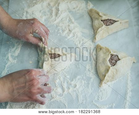 Baking peremech concept. Flour, dough and meat cooking ingredients. Hands top view of cooking belyash cuisines. ground meat with hole